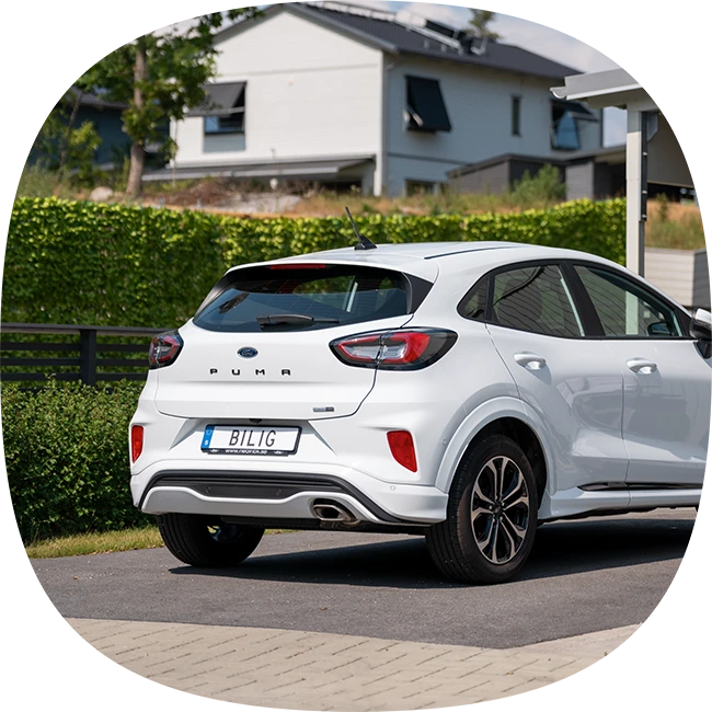 Vit bil parkerad på uppfart framför carport )