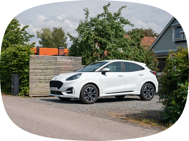 Vit bil parkerad på grusig uppfart framför en villa)